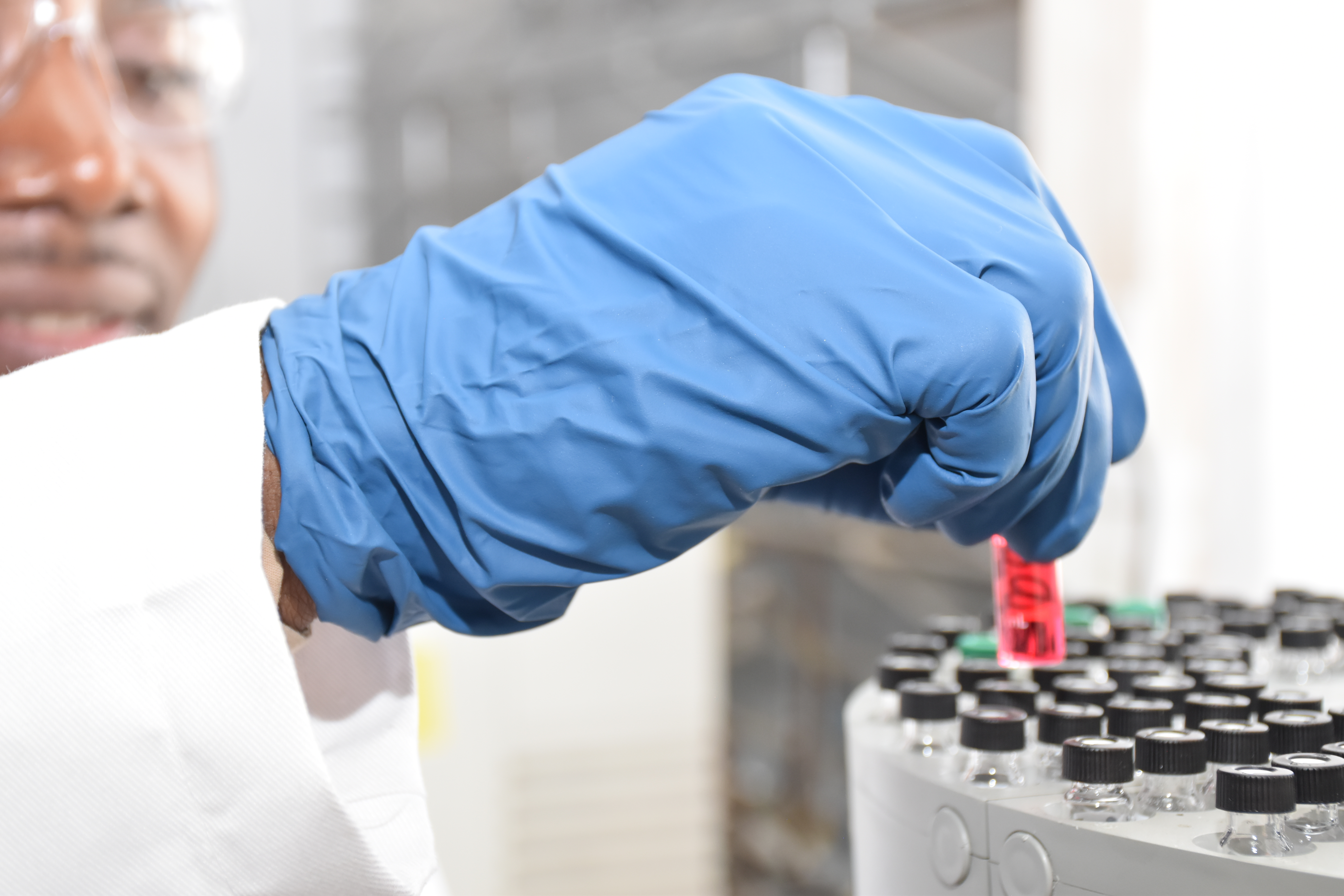 Close-up of a gloved hand holding a prepared sample vial in the laboratory.