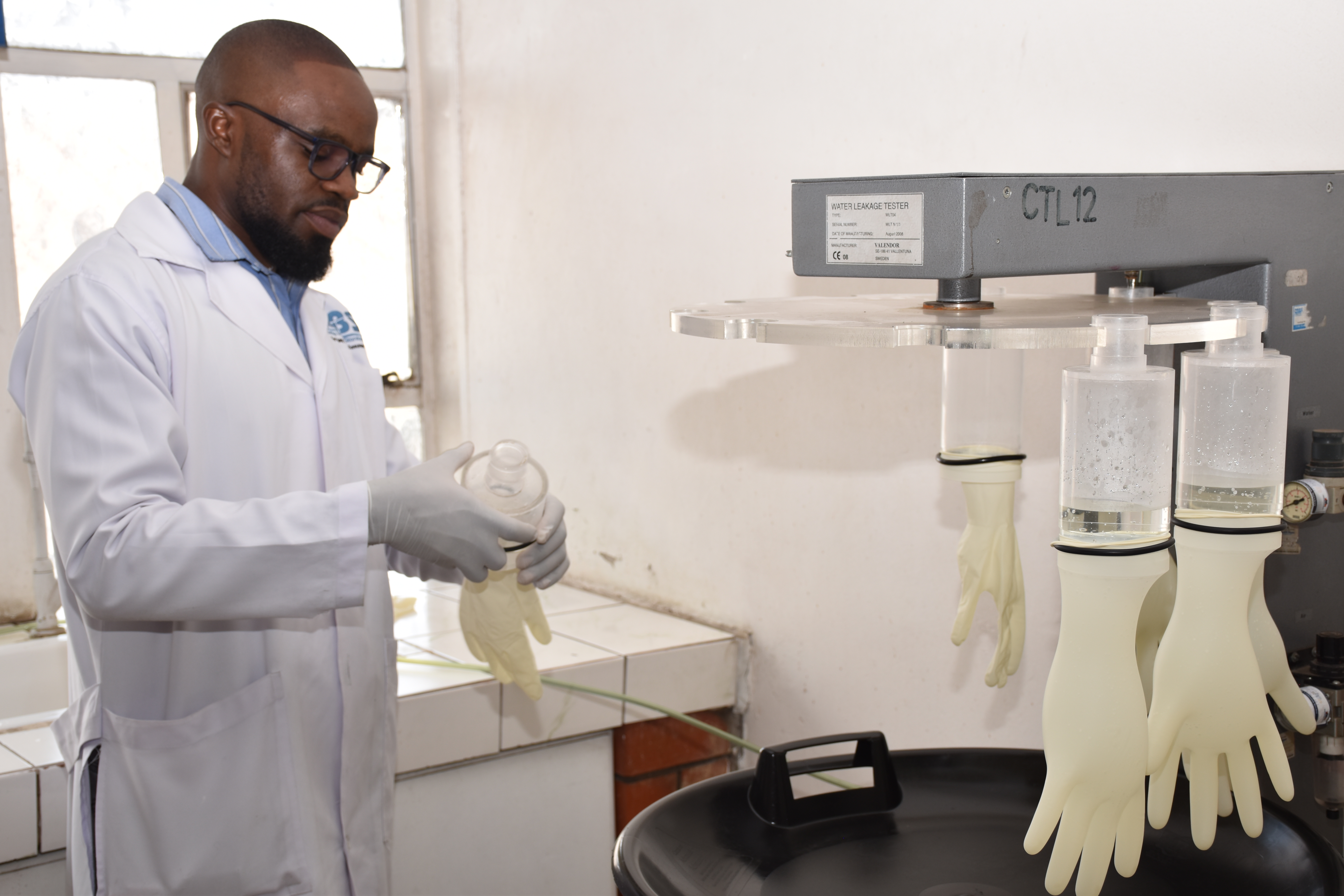 Technician preparing gloves and equipment for product leakage testing.
